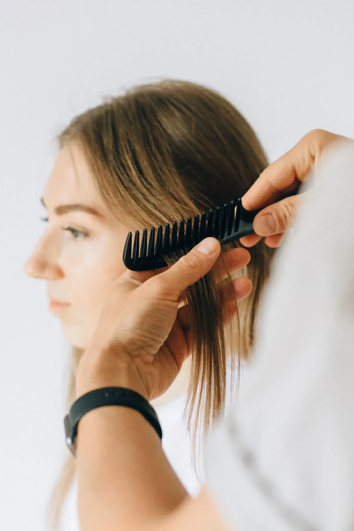 Haare werden Strähne für Strähne mit dem Kamm abgeteilt