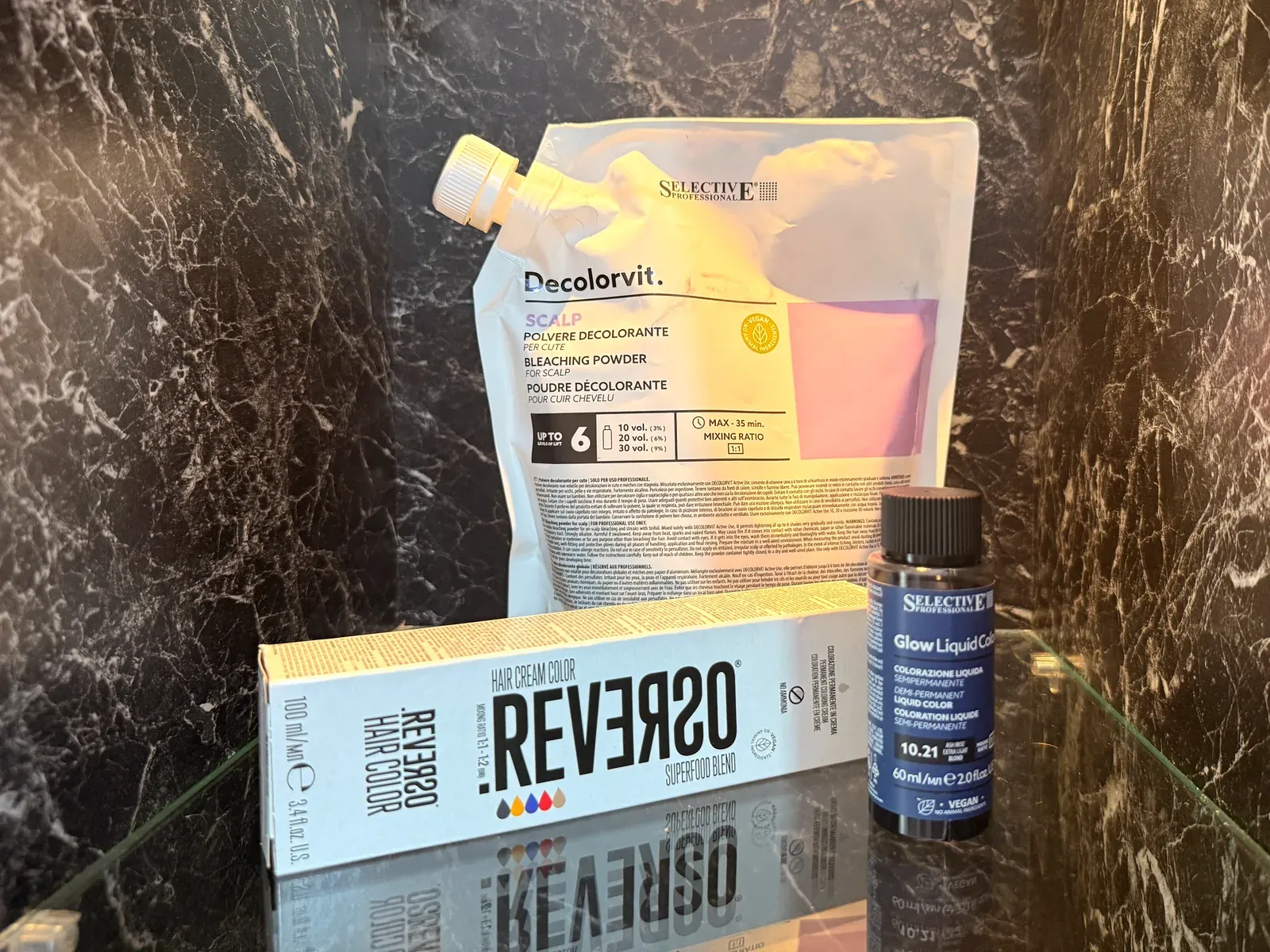 Decolorvit Blondierpulver, Reverso Hair Color und Glow Liquid Color auf der Marmorablage im Salon